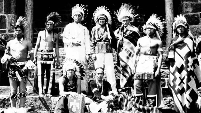 A historic photo shows Yuchi men in traditional clothing and feathered headdresses