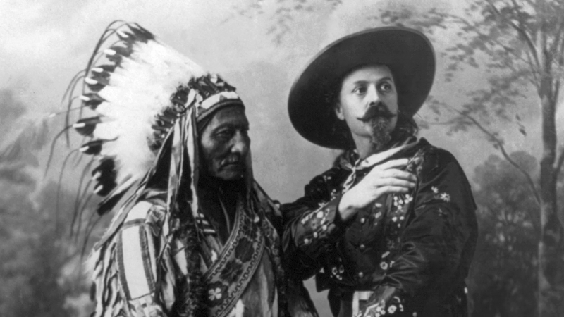 Sitting Bull stands beside Buffalo Bill Cody during his time with the Wild West Show